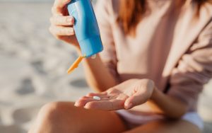 Mujer aplicándose fotoprotector solar en la playa para prevenir las manchas solares