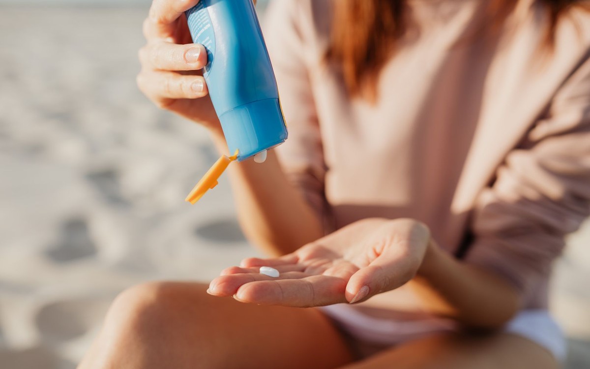 Mujer aplicándose fotoprotector solar en la playa para prevenir las manchas solares