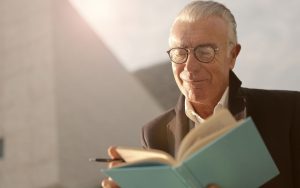 Hombre de mediana edad con gafas leyendo un libro, síntoma habitual de presbicia corregida