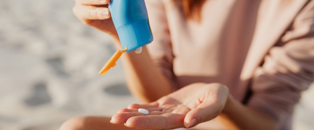 Mujer aplicándose fotoprotector solar en la playa para prevenir las manchas solares